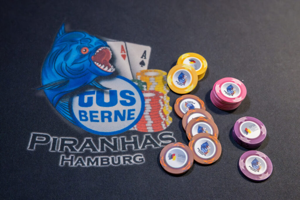 Vereinslogo auf dem Tischfilz, daneben Stapel farbiger Jetons mit dem Logo des Deutschen Poker Sportbundes